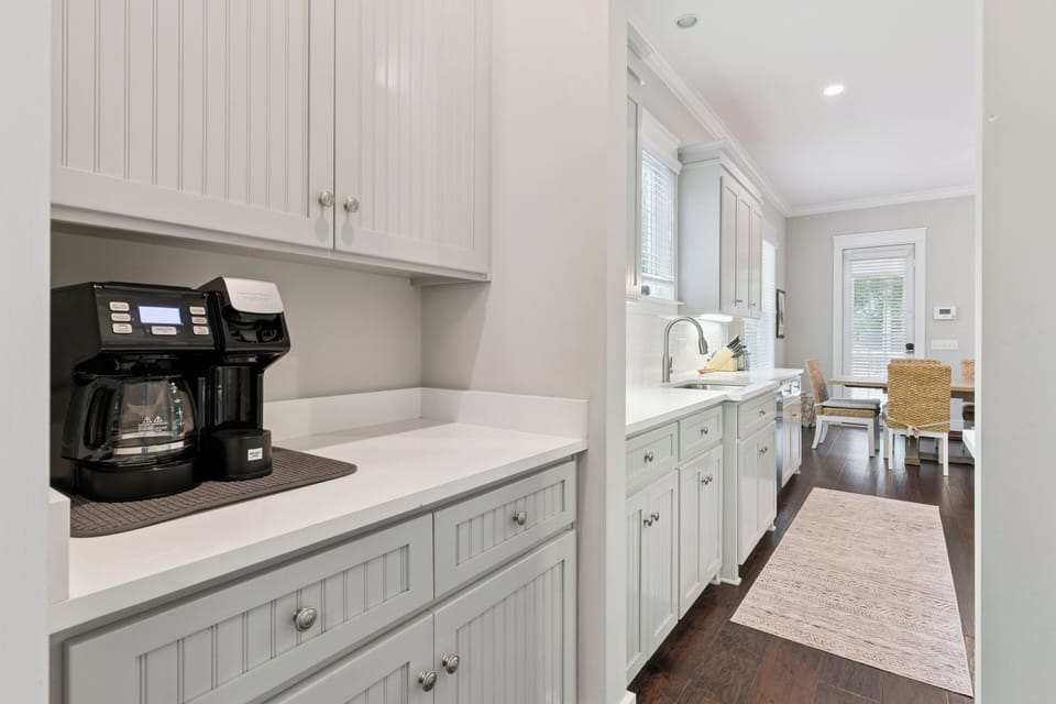 A bright, fully equipped kitchen awaits your culinary adventures, with crisp white cabinetry, modern appliances, and a dedicated coffee station to start your mornings right.