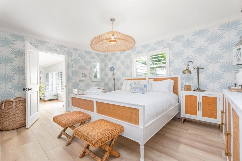 Drift off in this beautifully styled king bedroom, featuring coastal designer wallpaper, custom rattan accents, and a bright, calming Palm Beach–inspired feel.