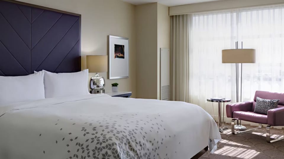 Unwind in crisp linens beneath a dramatic modern headboard.