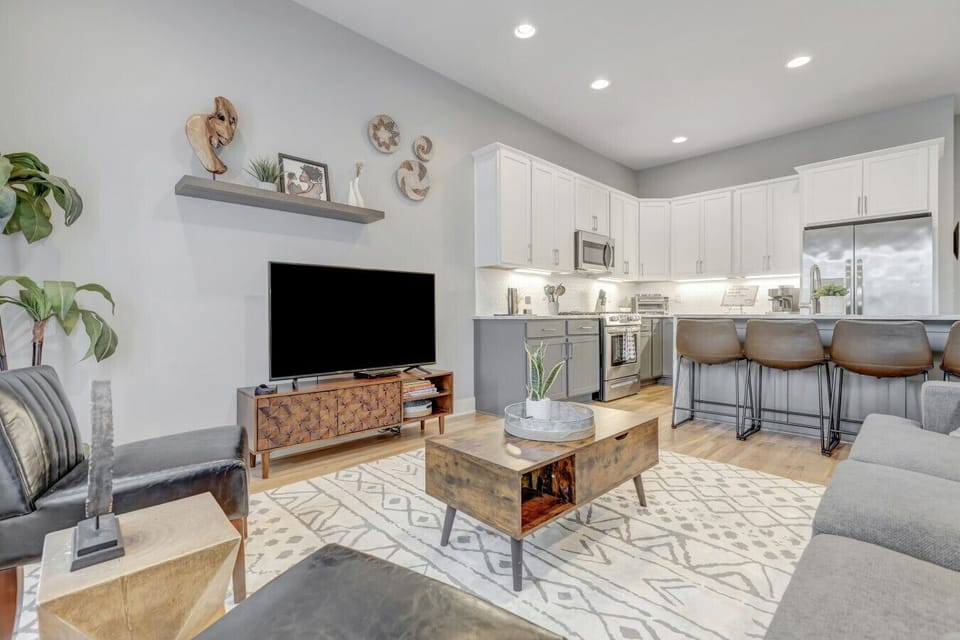 Modern open layout connecting the kitchen island bar to a cozy TV lounge corner.