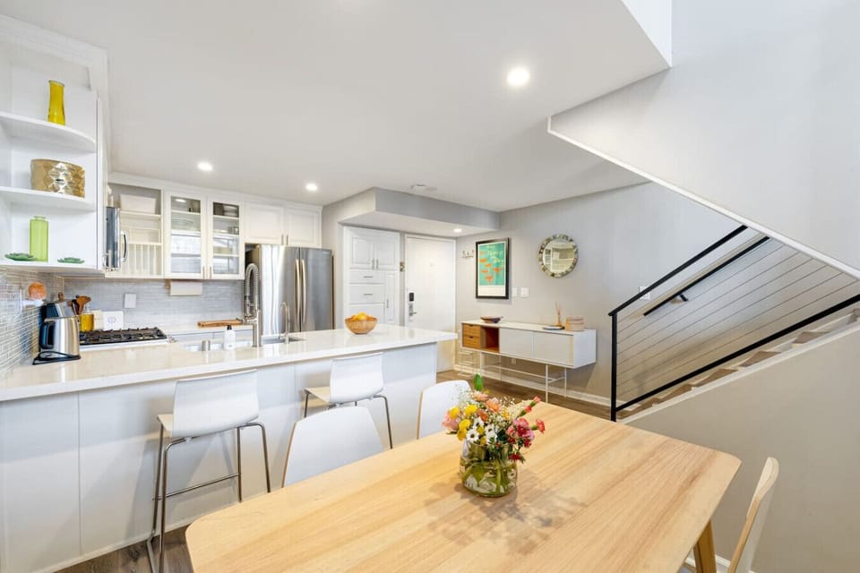 Enjoy meals together in this airy kitchen and dining area with modern design, island seating, and natural light throughout.