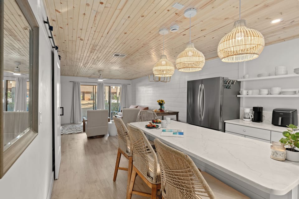 Long white breakfast bar with wicker stools and stylish woven pendant lights.