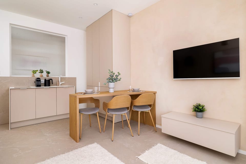 A wall-mounted TV is positioned across from the sofa, with a low-profile white cabinet providing extra storage.