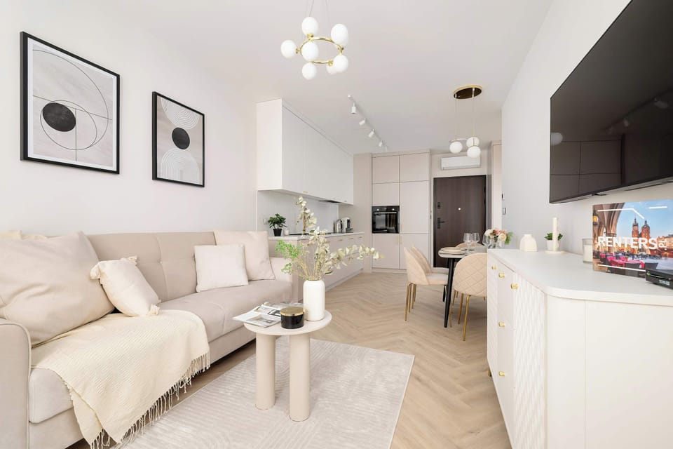 From this angle, the spaciousness of the living room is evident, featuring light-toned furniture that blends perfectly with the warm wooden floors.