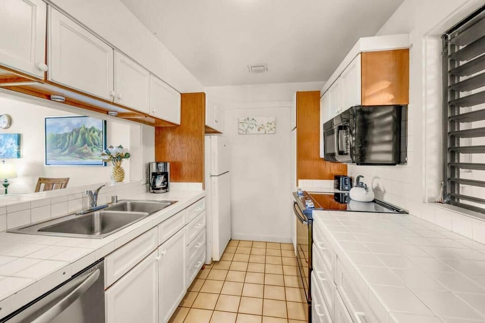 Bright galley kitchen with white cabinetry and warm wood accents.