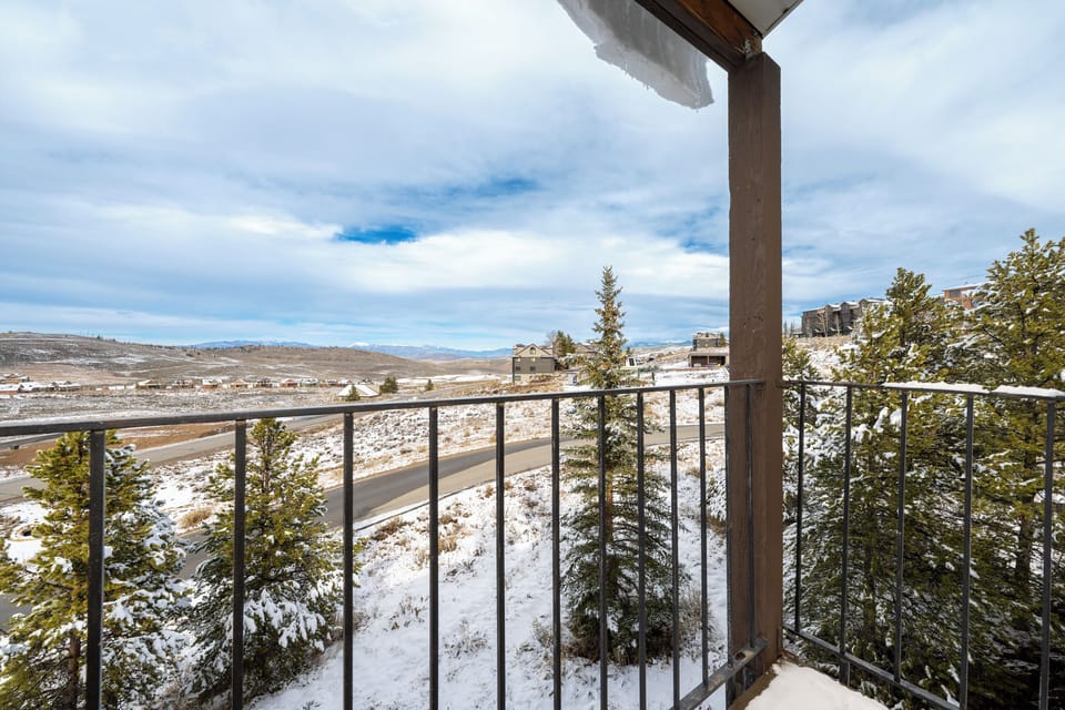 Panoramic winter mountain views at Mountainside Unit B-8 stretch endlessly from this scenic balcony overlooking snow-dusted landscapes and winding roads below.
