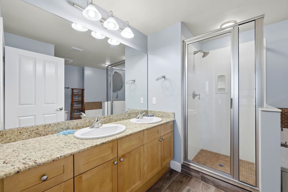 Modern bathroom with dual sinks and a glass-enclosed shower