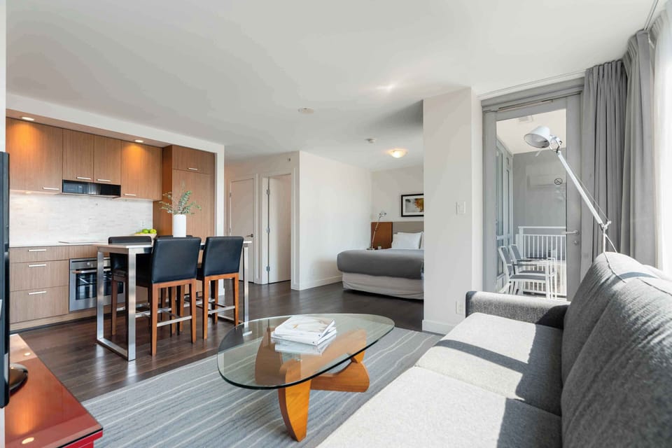Open-concept studio featuring a comfortable living area, glass coffee table, and full kitchen in one cohesive space.