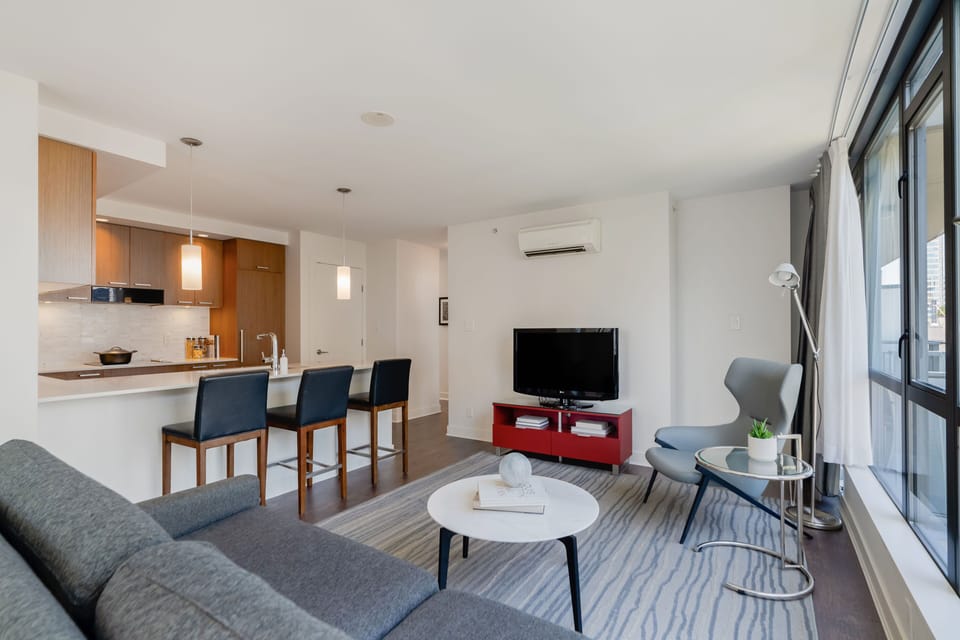 The open-concept living area boasts modern furnishings, a stylish kitchen, and large windows that flood the space with natural light.