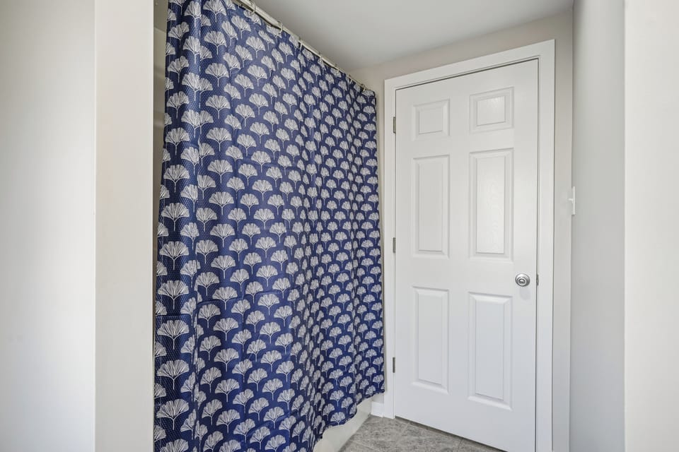 Step into your stylish entryway featuring elegant navy wallpaper with intricate shell patterns and crisp white details.
