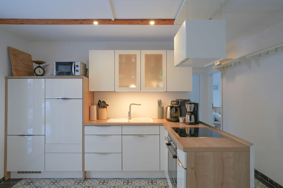 A bright, modern kitchen equipped with white cabinets, a cooktop, and appliances.