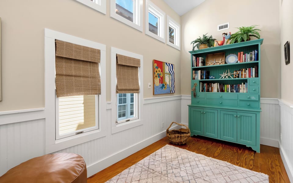 Curl up in your cozy reading nook with rich hardwood floors, charming wainscoting, and a stunning turquoise bookcase filled with stories.