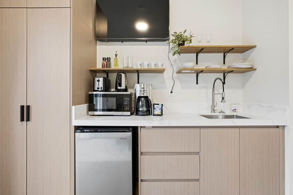 Kitchenette with microwave, kettle, coffee machine, toaster, sink, and mini fridge. 