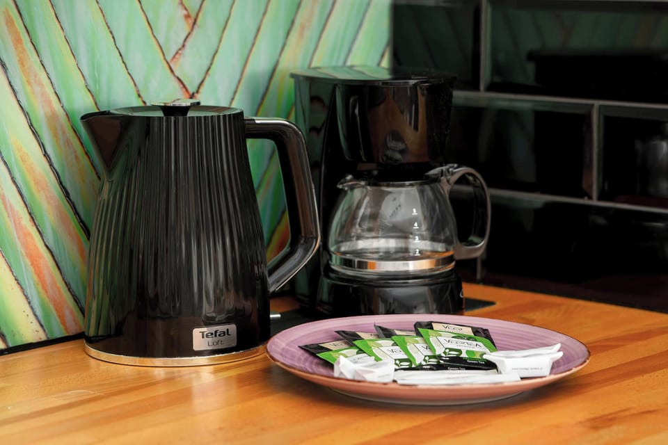 The kitchen counter is stocked with convenient amenities, including a black electric kettle and a coffee maker. A small plate of snacks is thoughtfully placed next to the appliances for guest enjoyment.