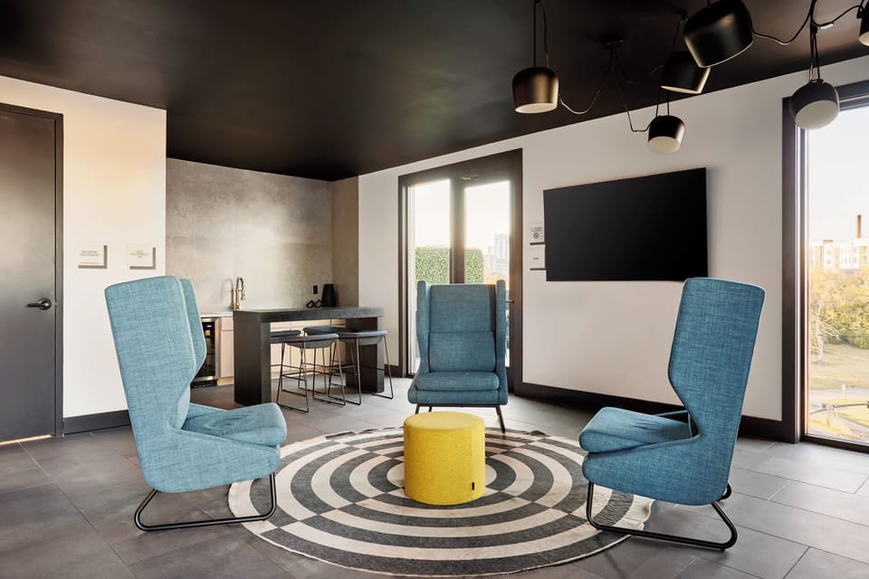 A stylish lounge space with modern seating, a TV, and a sleek kitchenette.