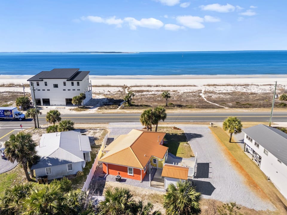 Charming orange beachfront cottage with palm trees and pristine white sand beach just steps away from the property.