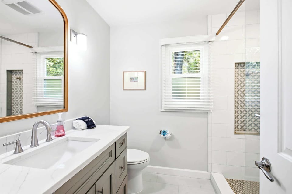 Modern bathroom with a marble countertop and patterned tile shower niche.