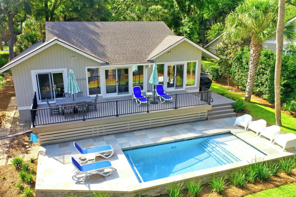 Sparkling blue water anchors this private poolside terrace, where sun-drenched stone tiles meet lush tropical greenery. Glass doors open wide to a spacious deck, creating a seamless flow for afternoon swims and alfresco dining under the palms.