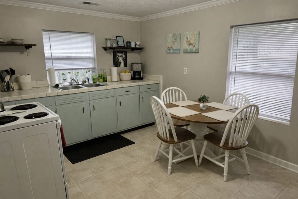 Eat‑in kitchen with dining table for four and large windows providing natural li