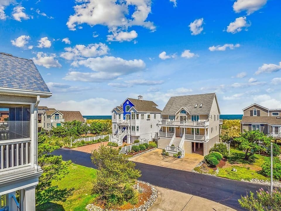 The charming architecture of the coastal homes displays a delightful mix of colors and styles, all framed by manicured lawns and the serene backdrop of the beach.