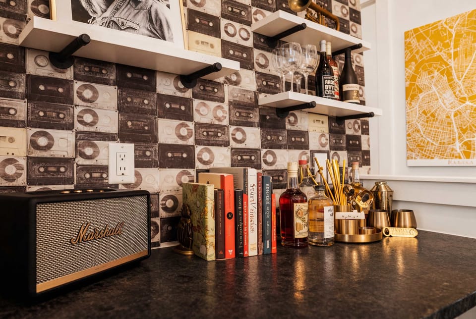 Marshall speaker, barware, and cassette-tape wallpaper turn the workspace into a retro-music lounge where someone can handle emails without leaving the party