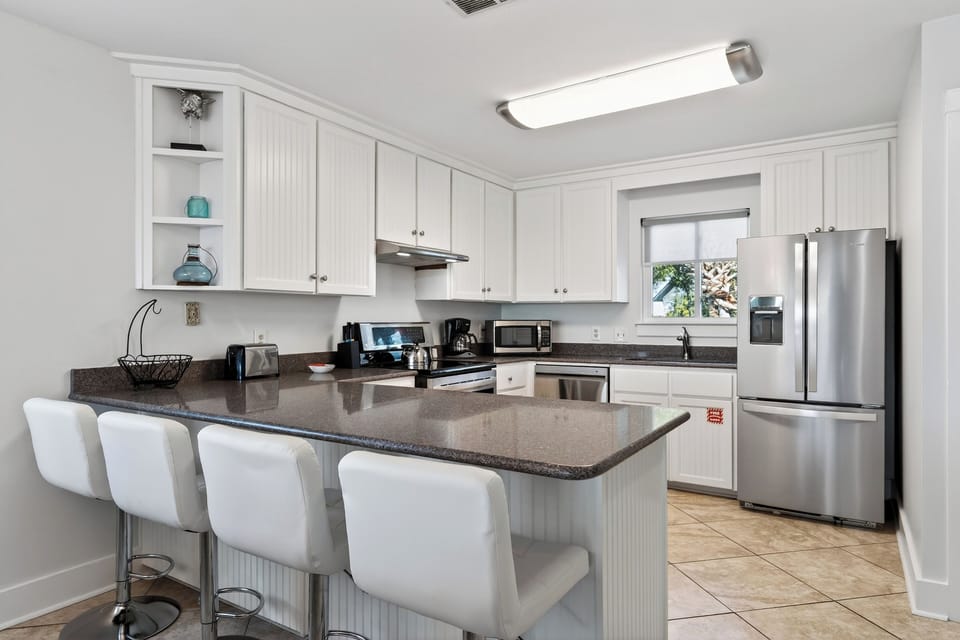 Fully equipped, coastal-bright kitchen with a big island—perfect for pancake stacks, snack spreads, and easy group meals.
