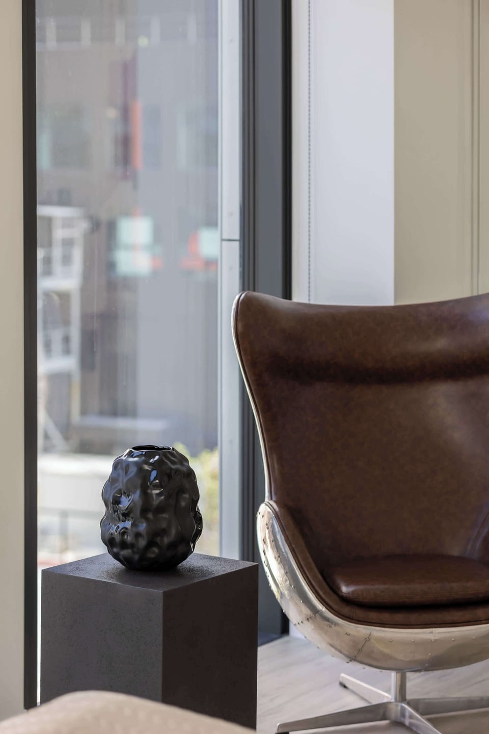 A close-up of a stylish light fixture and plant arrangement. The corner is cozy, perfect for a reading nook or relaxing moment.