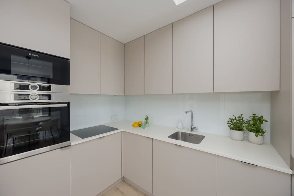 A contemporary kitchen with white cabinetry and modern lighting. The design emphasizes both functionality and elegance.