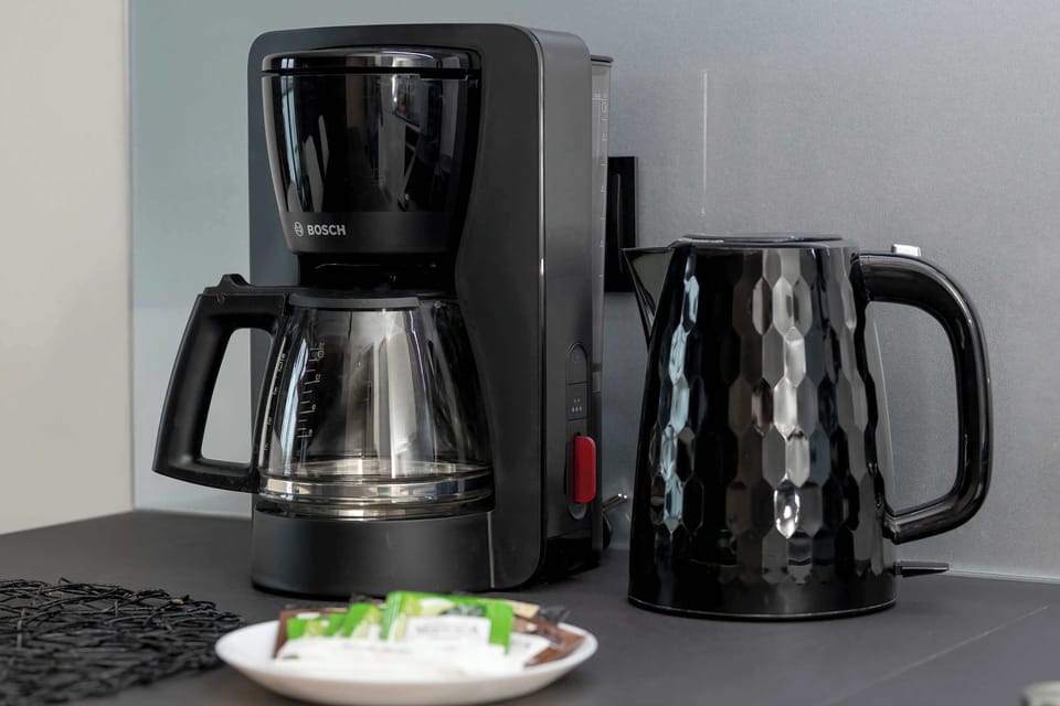 A dedicated coffee station is equipped with a modern drip coffee maker and a sleek black electric kettle.