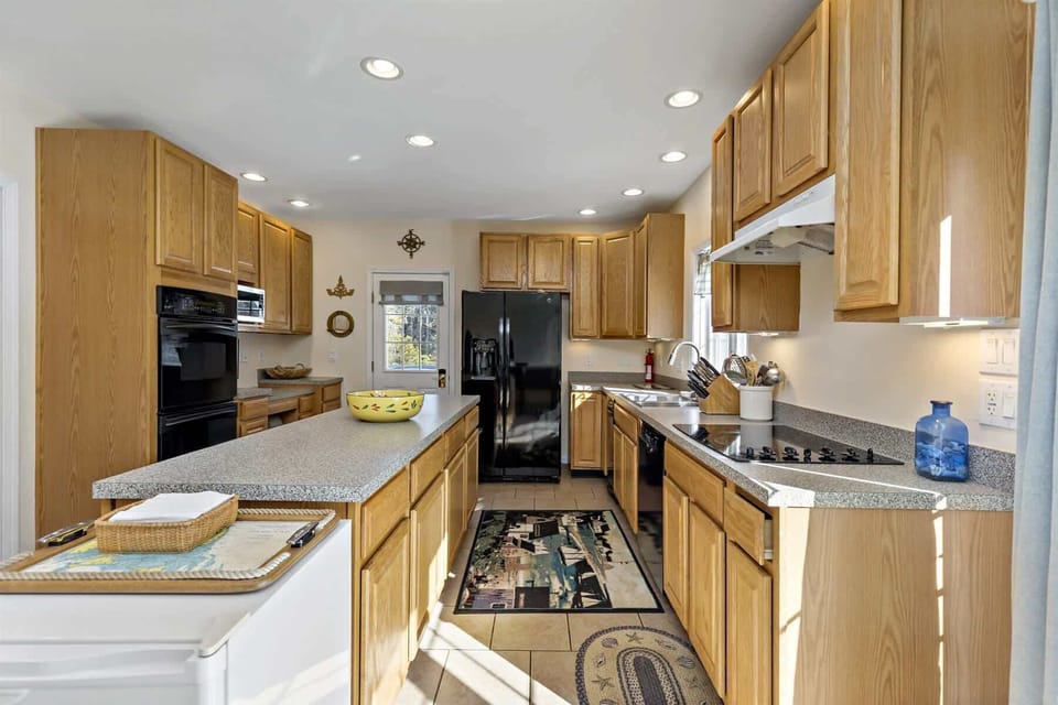 Well equipped Cape Cod kitchen with double ovens, full size appliances, and plenty of cabinetry for storing the essentials. 