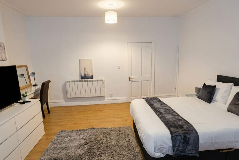 Bright double bedroom with a dedicated desk, TV, and generous wardrobe space for longer stays.