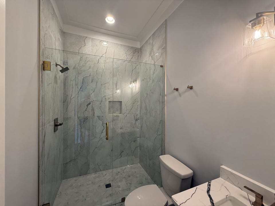 Step into your luxurious marble-clad bathroom featuring an elegant glass-enclosed shower and modern fixtures for your ultimate comfort.