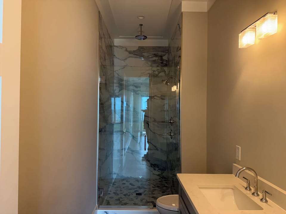 Your elegant bathroom features stunning marble tile work and a spacious glass-enclosed shower for a truly luxurious experience.