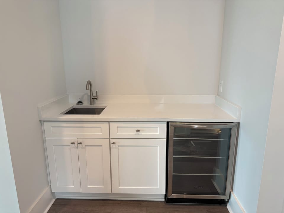 Your sleek kitchenette features white cabinetry, modern sink, and wine fridge—perfect for preparing light meals and chilling beverages during your stay.