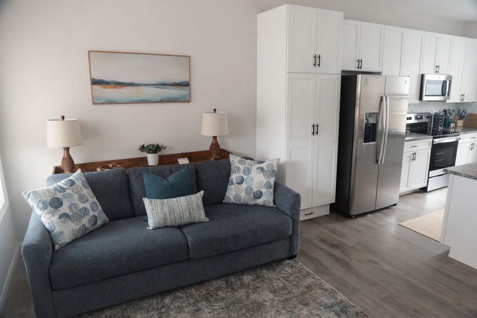 An effortless blend of style and function, this entry living space flows seamlessly into the kitchen. Settle in by the electric fireplace, unwind on the sofa, and ease into the rhythm of your retreat.
