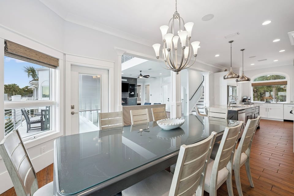 Gather around this elegant glass dining table where memorable meals unfold beneath stunning chandeliers, with your gourmet kitchen just steps away.