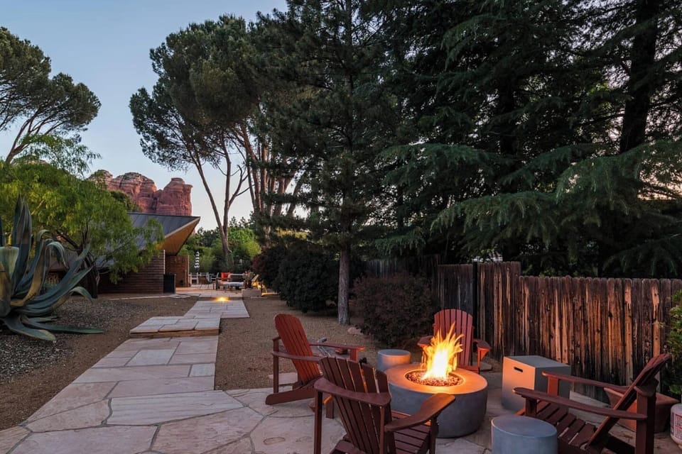 Inviting outdoor retreat featuring a cozy fire pit with Adirondack seating, serene desert landscaping, and stunning red rock views — the perfect spot to unwind under the evening sky.
