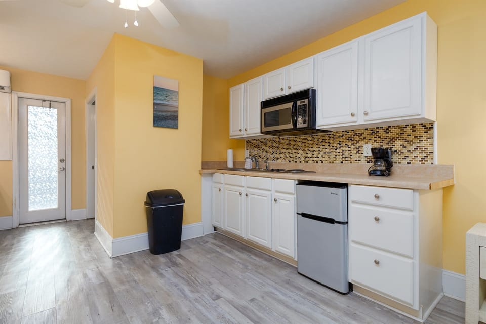 Fully equipped kitchenette with microwave, mini fridge, coffee maker, and ample cabinet space for easy meals.