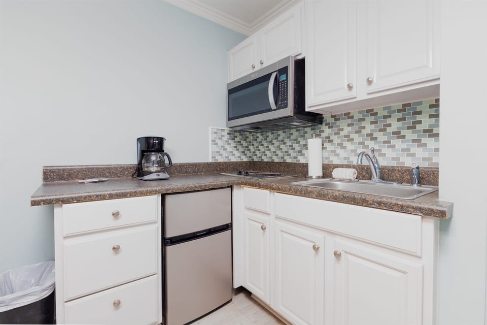 Convenient kitchenette with microwave, mini fridge, coffee maker, and sink for easy meals