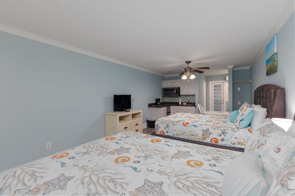 Open layout featuring two queen beds, a kitchenette, and dining area