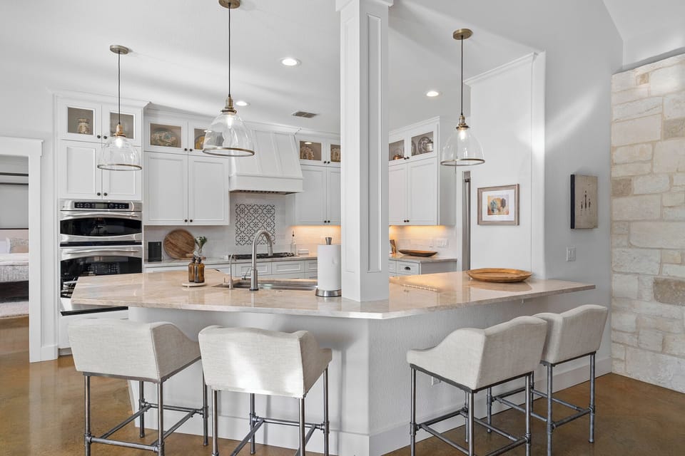 Marble countertops, brass pendant lights, double ovens, and enough island seating for the whole crew to gather around. Whether you're making a big group breakfast or just pouring the first round of drinks this kitchen was made for it.