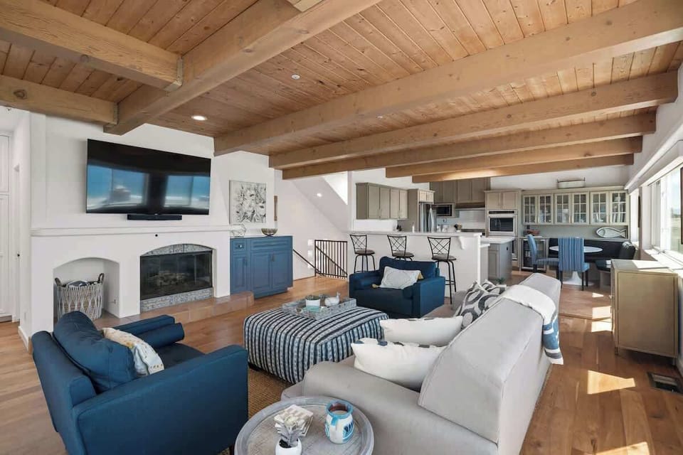 Inviting living room with exposed wood beam ceilings, fireplace, and an open layout that flows seamlessly into the kitchen.