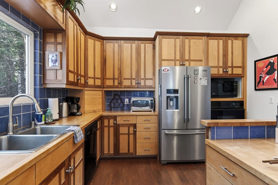 A bright, inviting kitchen with warm wood cabinetry, vaulted ceilings, and a spacious breakfast bar—perfect for morning coffee, shared meals, and easy entertaining.
