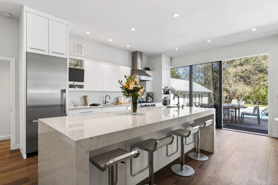 Bright, modern kitchen with waterfall island, premium appliances, and seamless indoor-outdoor flow to the pool deck.