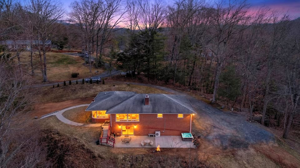 Twilight aerial: hot tub + fire pit, tucked into a quiet wooded retreat.