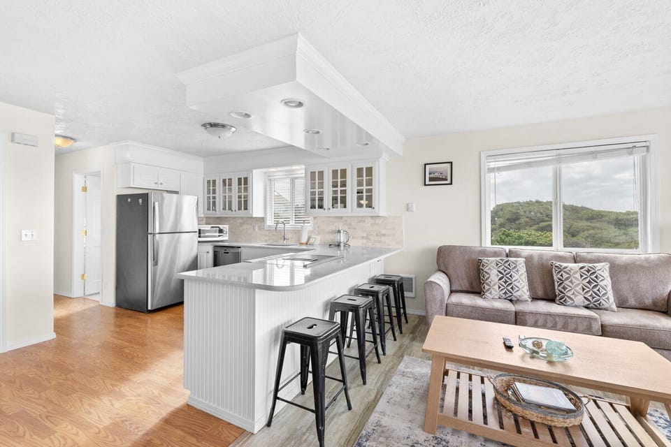 Your bright open-plan kitchen and living space flows seamlessly together, with modern appliances and forest views through large windows.