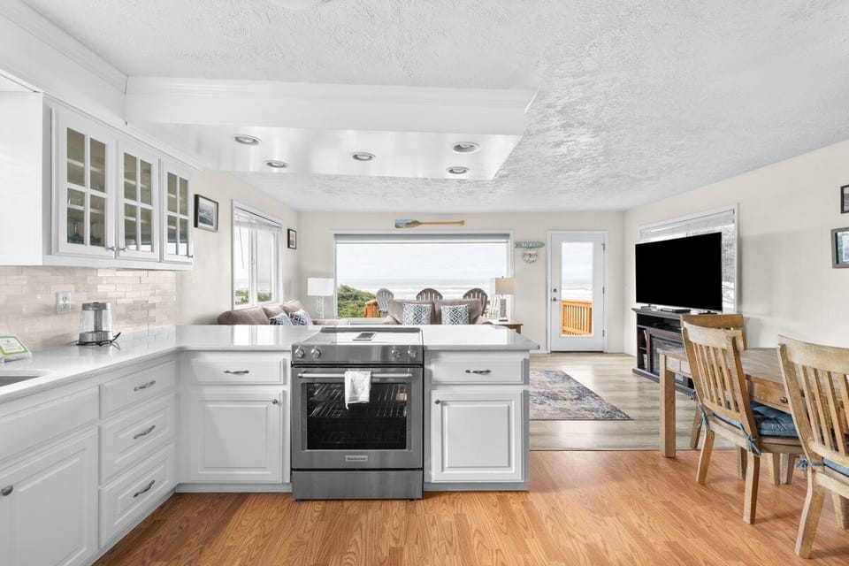 Cook memorable meals in this spacious kitchen featuring pristine white cabinetry, modern appliances, and a cozy dining area overlooking scenic views.