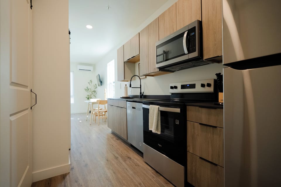 Cook your favorite meals in this sleek, modern kitchen featuring wood-grain cabinets, stainless steel appliances, and everything you need for a comfortable stay.