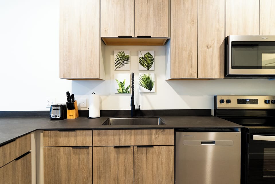 Your modern kitchen features sleek counters, stainless appliances, and charming botanical artwork—perfect for preparing meals in style.