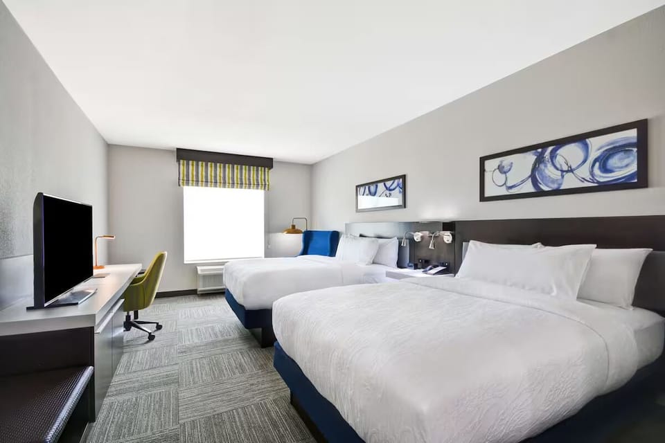Unwind in bright double-queen comfort with TV and work desk.